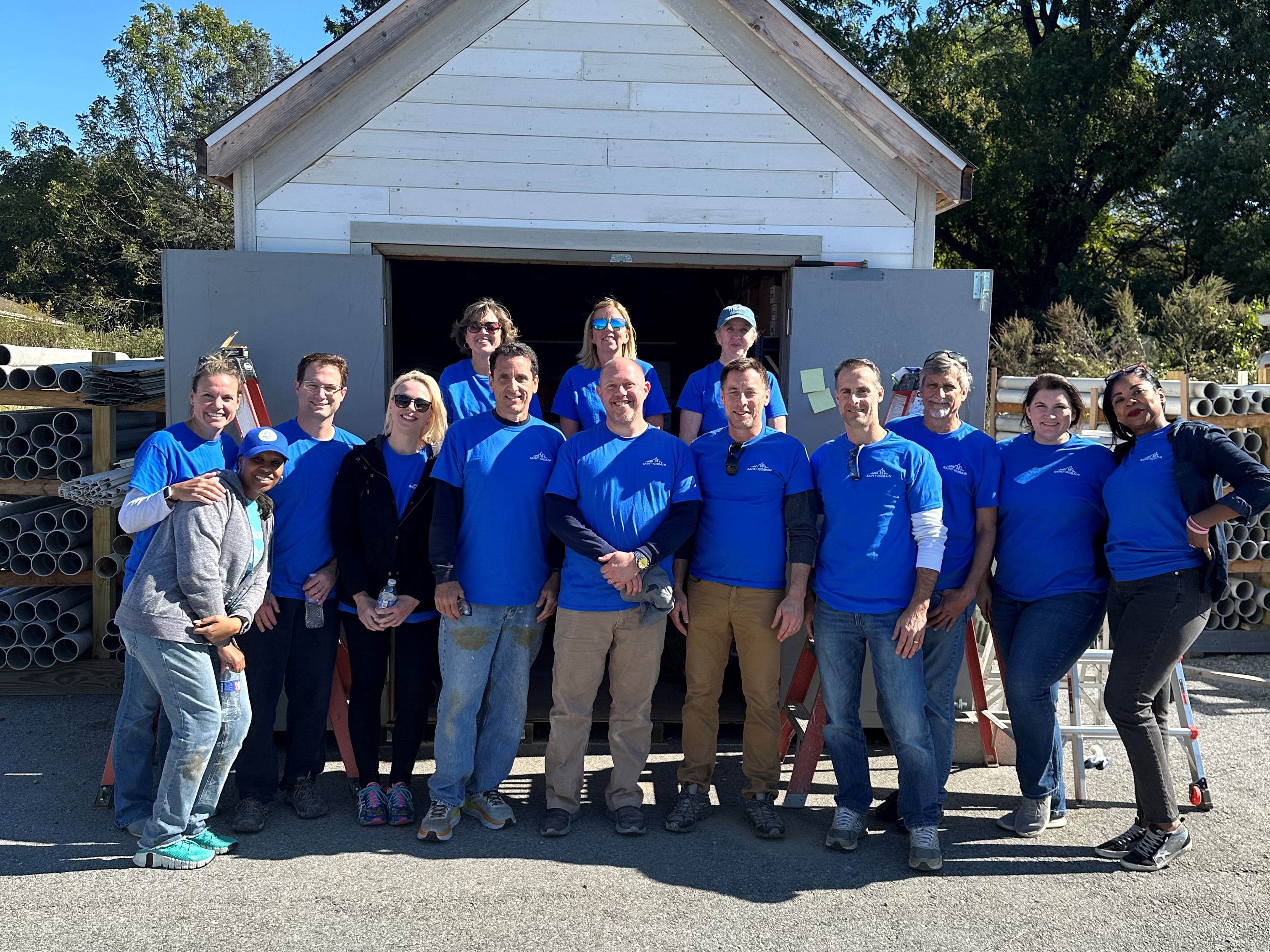 A group of people pose in front of a shed